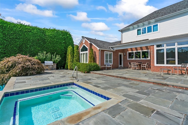 view of pool with an in ground hot tub, exterior kitchen, and a patio