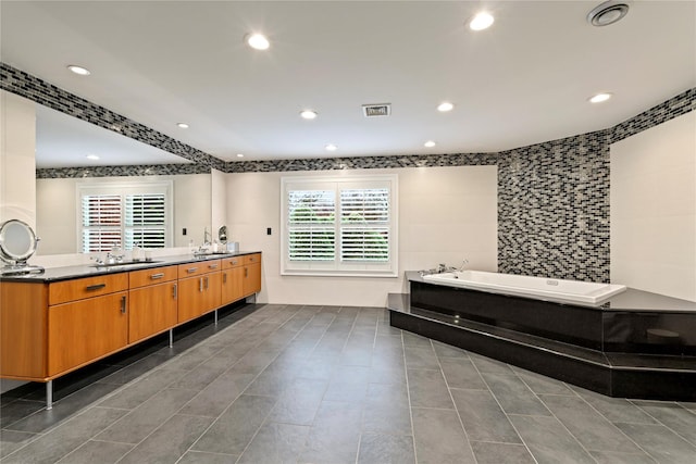 bathroom with a washtub, vanity, tile walls, and tile patterned flooring