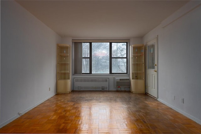 empty room featuring radiator heating unit, parquet flooring, and a wall mounted AC