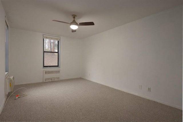 carpeted empty room with radiator and ceiling fan