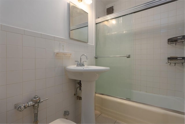 bathroom with enclosed tub / shower combo, tile walls, and toilet