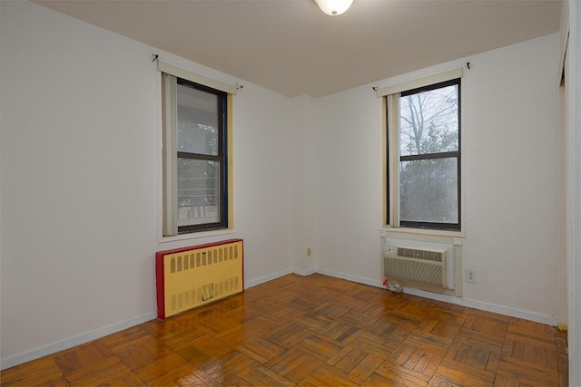 unfurnished room featuring a wall mounted AC, dark parquet floors, and radiator