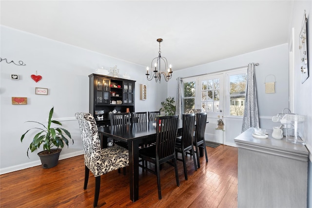 dining space with dark hardwood / wood-style flooring and a chandelier