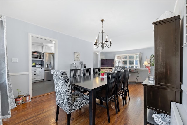 dining area featuring dark wood-type flooring and an inviting chandelier