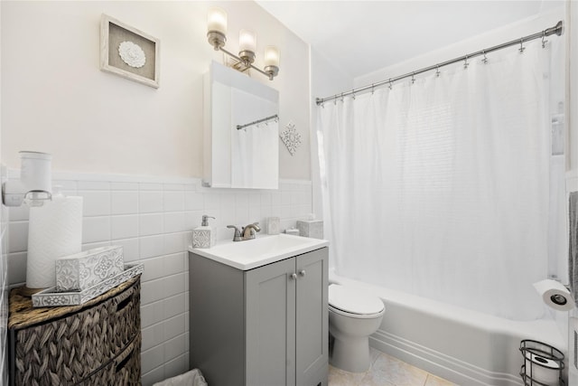 full bathroom featuring shower / bathtub combination with curtain, tile patterned flooring, toilet, vanity, and tile walls