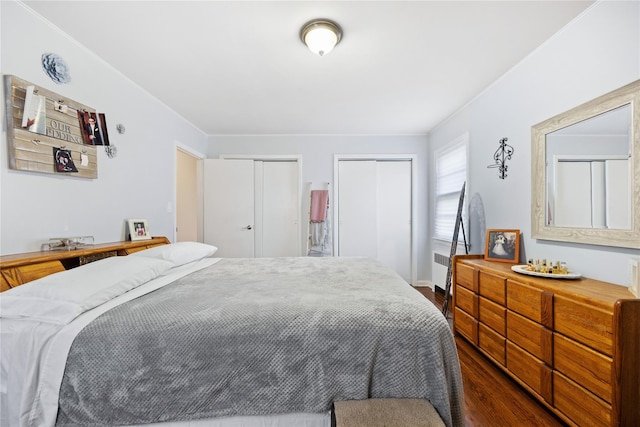 bedroom featuring radiator, dark hardwood / wood-style floors, and multiple closets