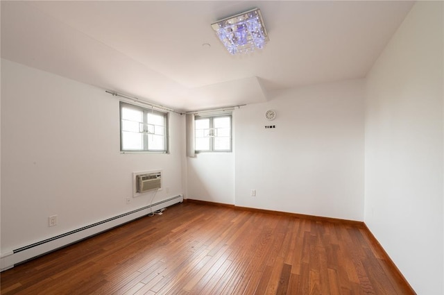 spare room with an AC wall unit, wood-type flooring, and a baseboard heating unit