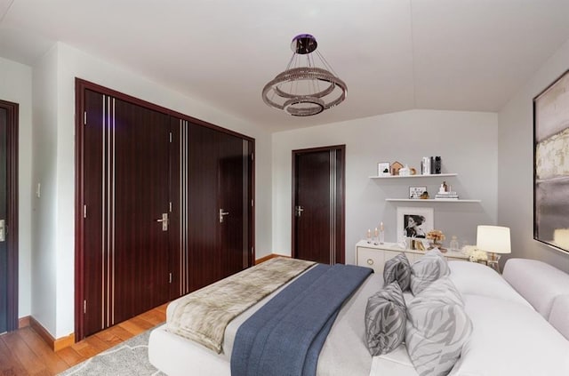 bedroom with light hardwood / wood-style floors, a closet, and lofted ceiling