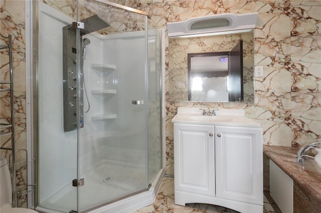 bathroom featuring a shower with door and vanity