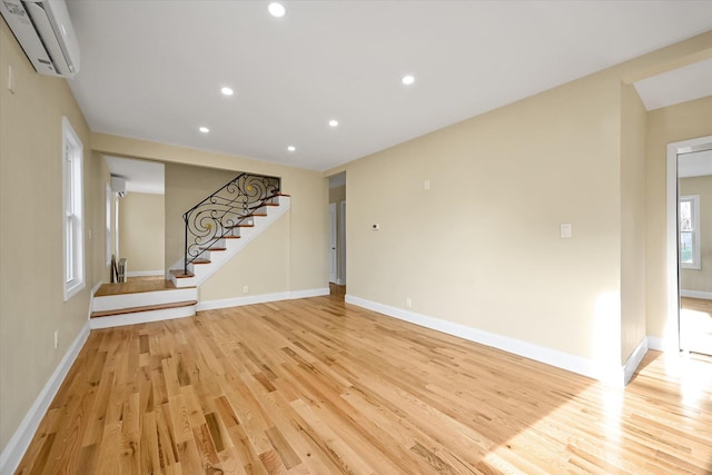 unfurnished living room featuring light hardwood / wood-style floors and a wall mounted AC