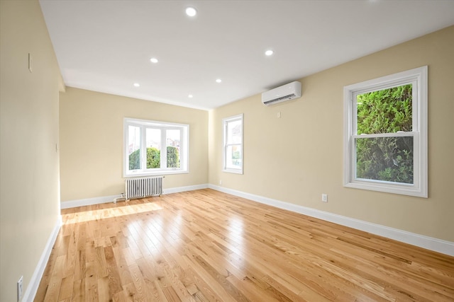 empty room featuring radiator, light hardwood / wood-style floors, and a wall mounted AC