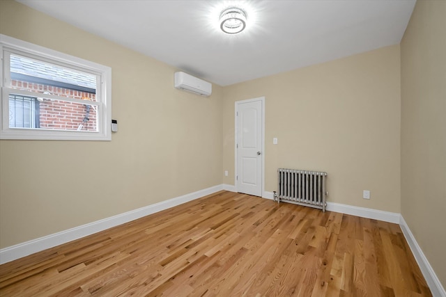 empty room with radiator heating unit, light hardwood / wood-style flooring, and a wall unit AC