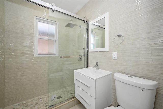 bathroom with an enclosed shower, vanity, toilet, and tile walls