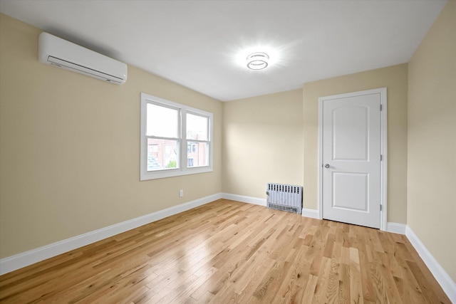 unfurnished room featuring an AC wall unit, radiator heating unit, and light wood-type flooring