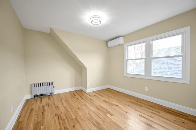 bonus room featuring an AC wall unit, radiator, and light hardwood / wood-style floors