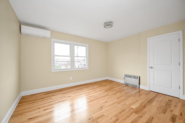 empty room featuring radiator heating unit, light hardwood / wood-style floors, and an AC wall unit