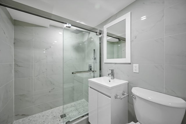 bathroom featuring walk in shower, vanity, toilet, and tile walls