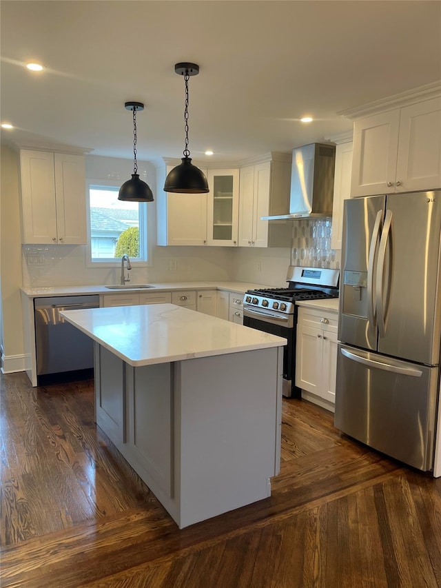 kitchen with stainless steel appliances, sink, wall chimney range hood, a center island, and white cabinetry