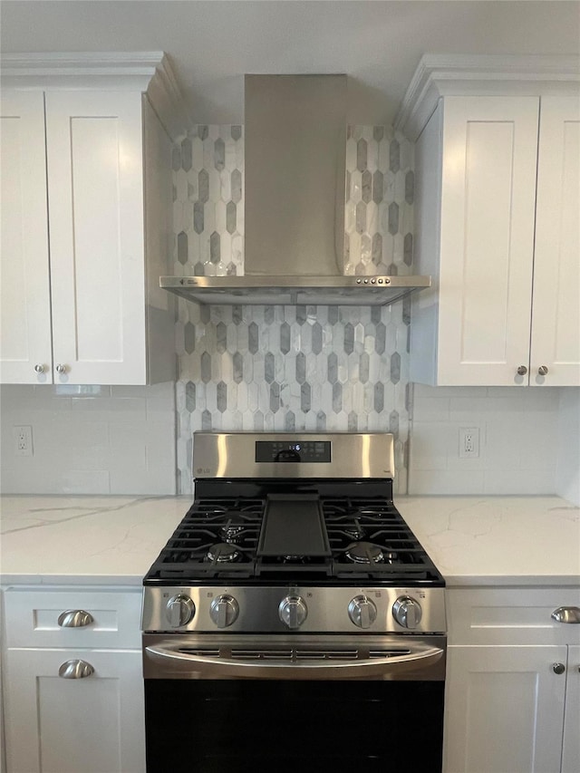 kitchen featuring white cabinets, stainless steel gas stove, decorative backsplash, and wall chimney range hood