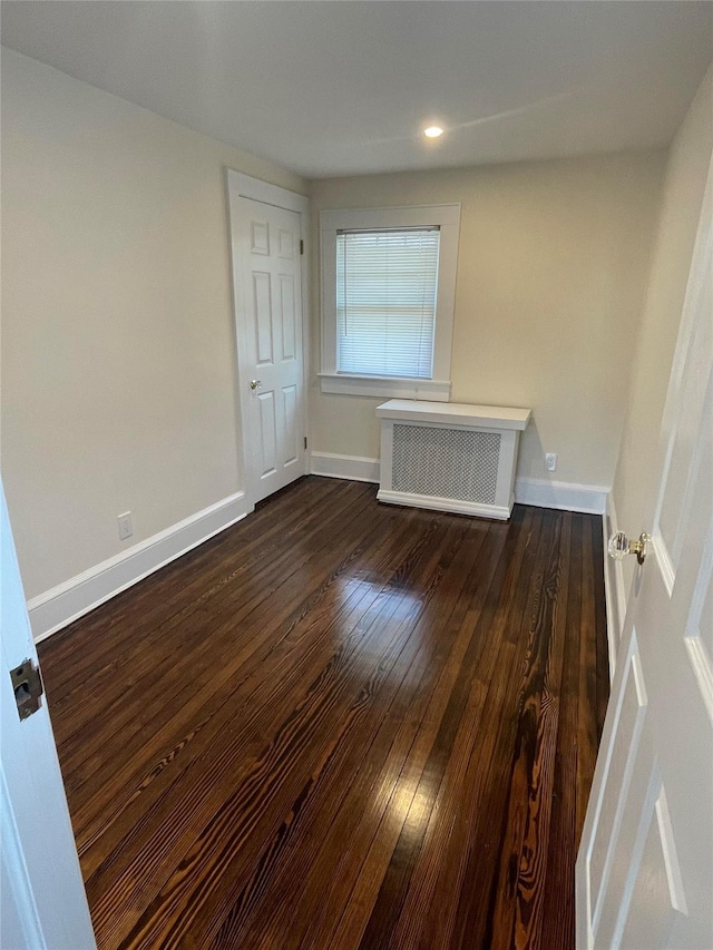 unfurnished room featuring radiator and dark hardwood / wood-style flooring