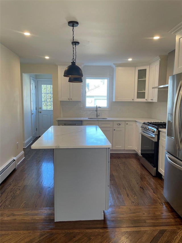 kitchen with sink, hanging light fixtures, stainless steel appliances, a kitchen island, and white cabinets