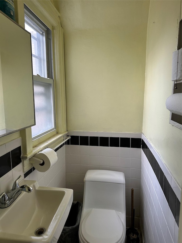 bathroom featuring toilet, sink, and tile walls