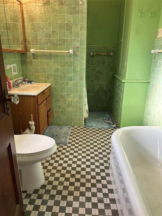 bathroom featuring a bathing tub, vanity, toilet, and tile walls