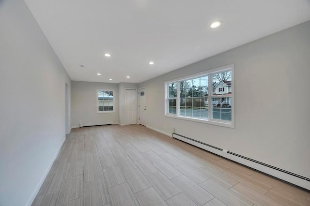 empty room featuring a baseboard heating unit and a wealth of natural light