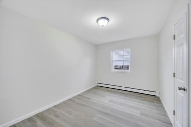 spare room featuring baseboard heating and light hardwood / wood-style flooring