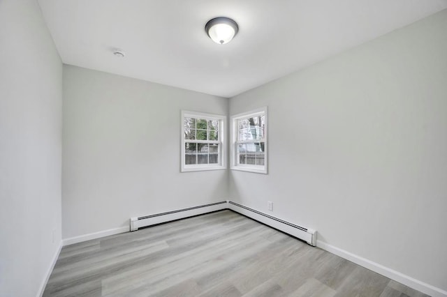 spare room featuring baseboard heating and light hardwood / wood-style floors