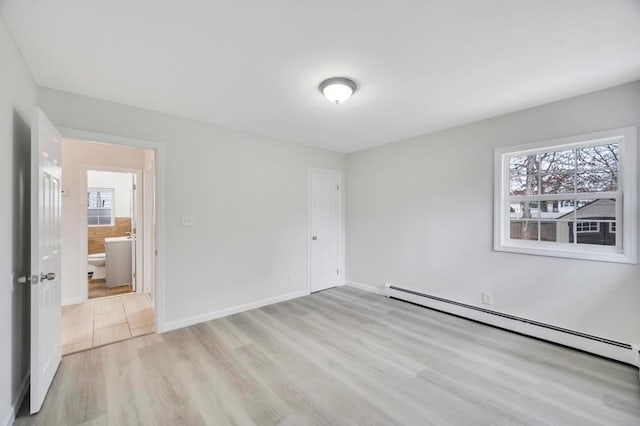 unfurnished bedroom with baseboard heating, light wood-type flooring, and ensuite bath