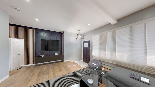 unfurnished living room with beamed ceiling, light hardwood / wood-style floors, and a baseboard heating unit