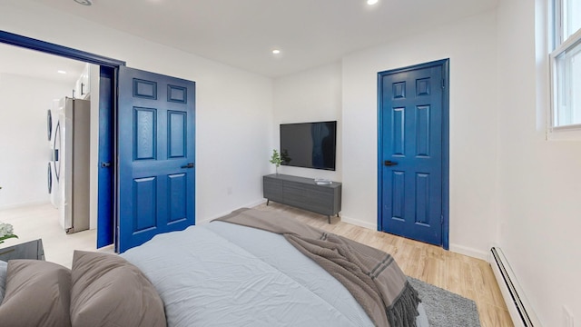 bedroom featuring stainless steel fridge, light hardwood / wood-style flooring, and a baseboard radiator