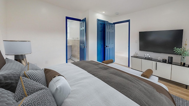 bedroom with connected bathroom and light wood-type flooring