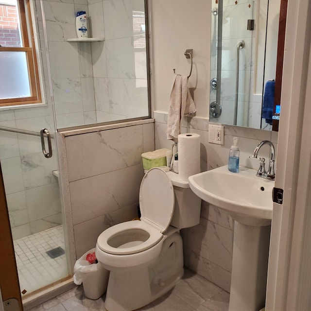 bathroom with sink, a shower with door, tile walls, and toilet