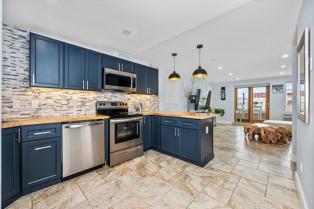 kitchen featuring blue cabinetry, wooden counters, kitchen peninsula, decorative light fixtures, and appliances with stainless steel finishes