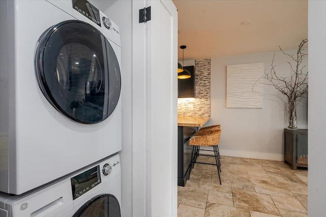 clothes washing area featuring stacked washer and clothes dryer