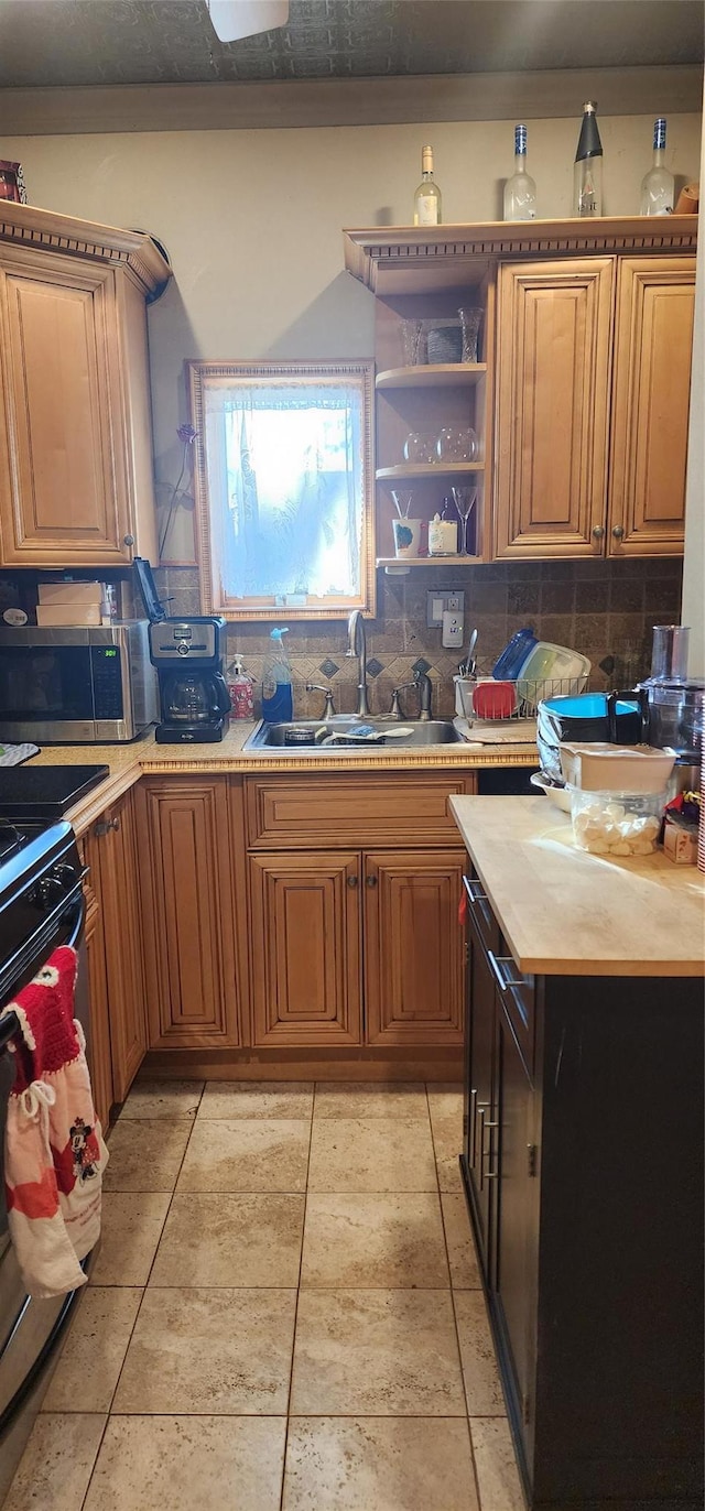 kitchen with sink, light tile patterned floors, butcher block countertops, decorative backsplash, and appliances with stainless steel finishes