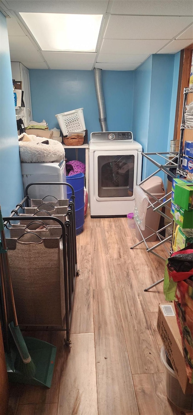 clothes washing area featuring light wood-type flooring and washer and clothes dryer