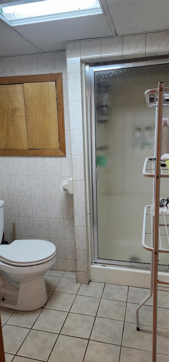 bathroom featuring tile walls, tile patterned flooring, an enclosed shower, and toilet