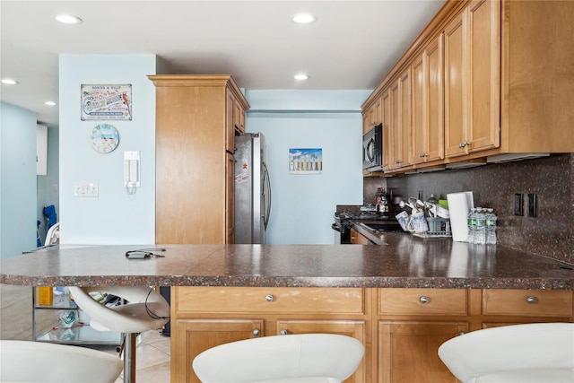 kitchen with backsplash, stainless steel fridge, and kitchen peninsula