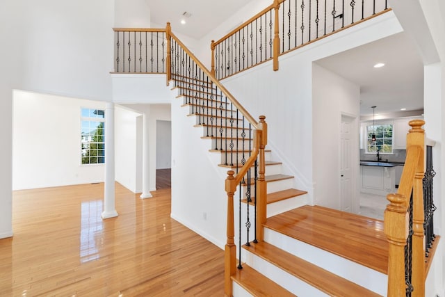 stairs with hardwood / wood-style floors, plenty of natural light, and a high ceiling