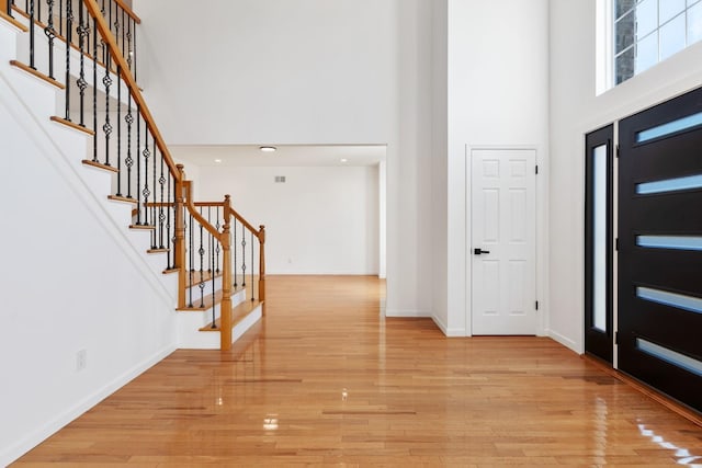 entrance foyer with a towering ceiling and light hardwood / wood-style flooring