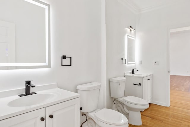 bathroom featuring toilet, ornamental molding, hardwood / wood-style floors, and vanity