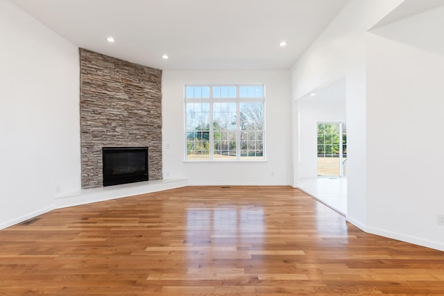 unfurnished living room with a stone fireplace and light hardwood / wood-style flooring