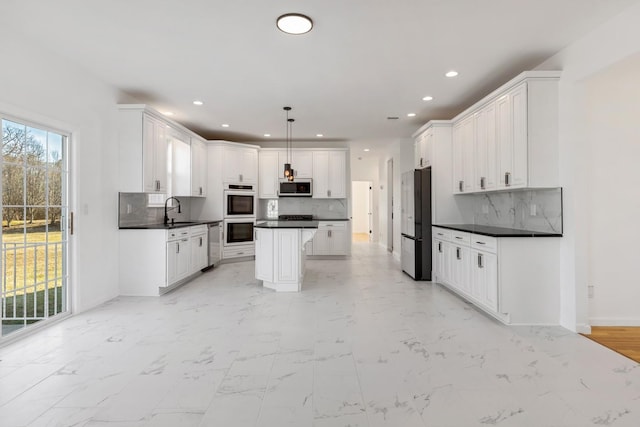 kitchen with white cabinetry, stainless steel appliances, a center island, decorative light fixtures, and sink