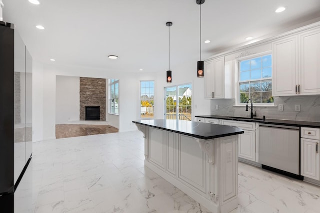 kitchen with stainless steel dishwasher, white cabinets, sink, and pendant lighting