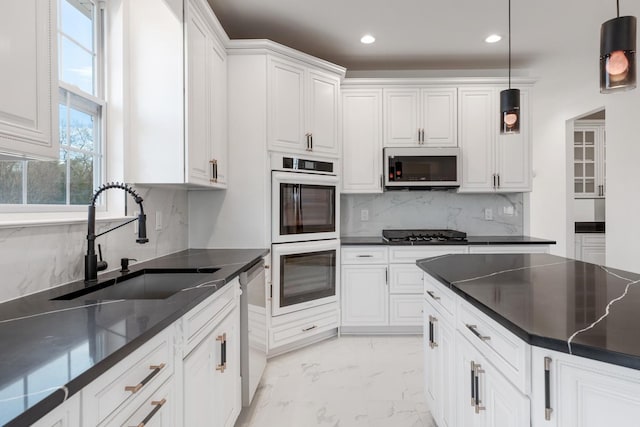 kitchen with appliances with stainless steel finishes, decorative backsplash, hanging light fixtures, white cabinets, and sink