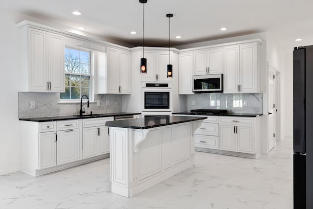 kitchen featuring black refrigerator, decorative light fixtures, a kitchen island, white cabinets, and sink