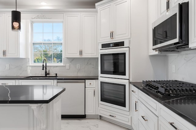 kitchen featuring stainless steel appliances, backsplash, pendant lighting, white cabinets, and sink